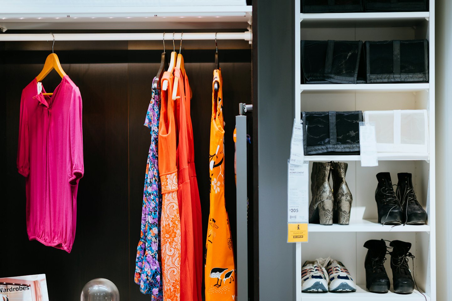 Retail wardrobe system displaying clothing and organized footwear on shelving.